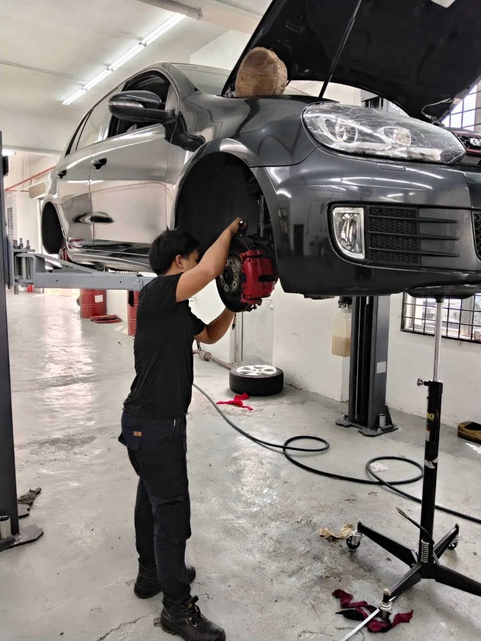 A Toyokar technician carrying out repair work beside a vehicle raised on a workshop lift